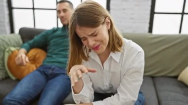 Arka planda bir erkekle oturma odasında ağlayan perişan bir kadın bir ilişkideki gerilimi tasvir ediyor..