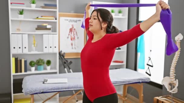 Молодая Латиноамериканка Клинике Физиотерапии Проводит Упражнения Растяжку Браслетом Сопротивления — стоковое видео