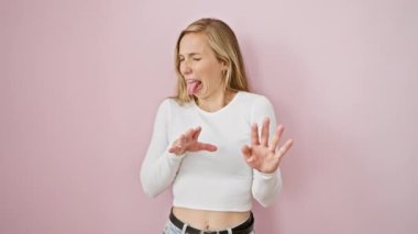 İğrençleşmiş genç sarışın kadın korkuyla tiksinmiş yüzünü çeker. Pembe izole edilmiş arka planda el sallayarak kaçınma tepkisi verir.