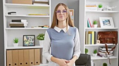 Gülümseyen genç sarışın iş kadını sevinçle ofisini işaret ediyor, 