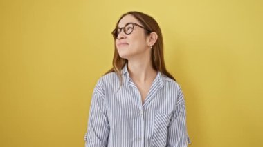 Mavi gözlü, gözlüklü, bakışları süzülürken düşüncelere dalmış genç bir kadın. Güneşli, izole, sarı bir zemin üzerinde yakalanmış, kurnazca gülümseyen, neşe dolu!