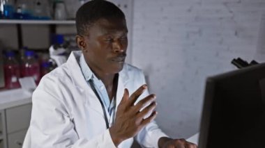 Modern bir laboratuvar ortamında bilgisayar ekranındaki verileri analiz eden odaklanmış bir siyah adam.