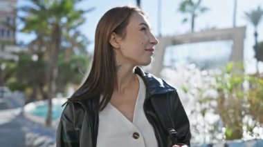 Kafkasyalı kadın, güneşli şehir caddesinde sakin ve meraklı bir şekilde kentsel çevreyi düşünüyor..