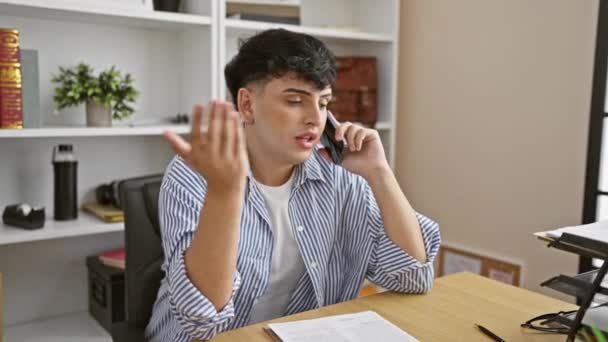 本と机のあるオフィスの設定で電話で話すイラストの若い男 — ストック動画
