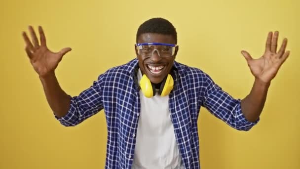 快乐的非洲裔美国人 戴着安全眼镜 站在黄色孤立的背景上 满面春风 喜形于色地庆祝胜利 兴奋和胜利的表现 — 图库视频影像