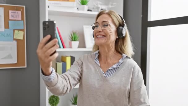 Smiling Mature Woman Headphones Conducting Video Call Her Smartphone Office — Stock Video