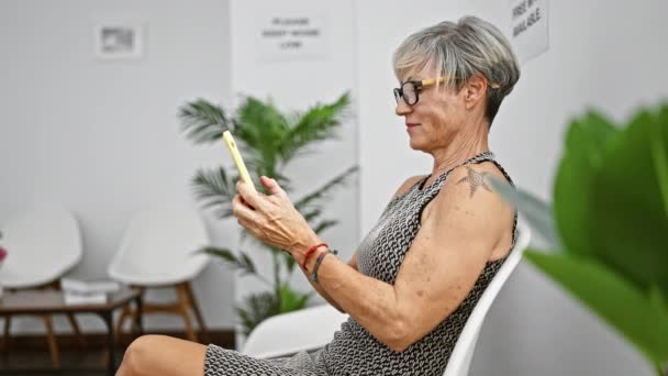 Mujer Mayor Con Gafas Texto Smartphone Una Moderna Sala Espera — Vídeos de Stock