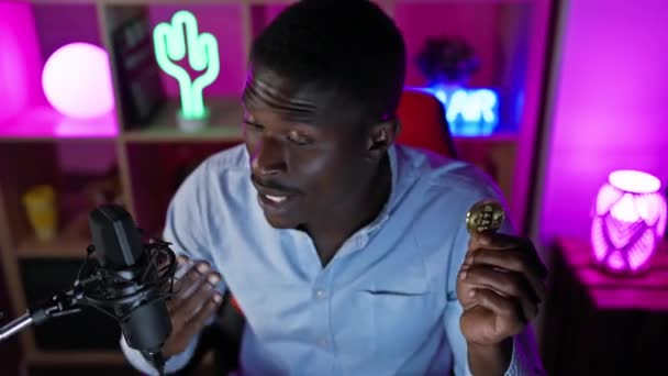 非洲男子持有比特币在霓虹灯播客演播室的夜晚 — 图库视频影像
