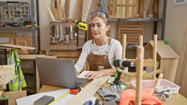 Dojrzała Kobieta Pracuje Laptopem Warsztacie Stolarskim Otoczona Narzędziami Drewnem — Wideo stockowe