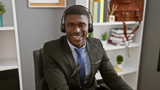 現代オフィスでカスタマーサービスで働くヘッドセットを持つ笑顔のアフリカ人男性 — ストック動画