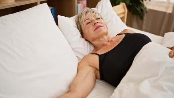 安详的中年女性 灰白的头发 躺在房间里 躺在白色的床单上休息 — 图库视频影像