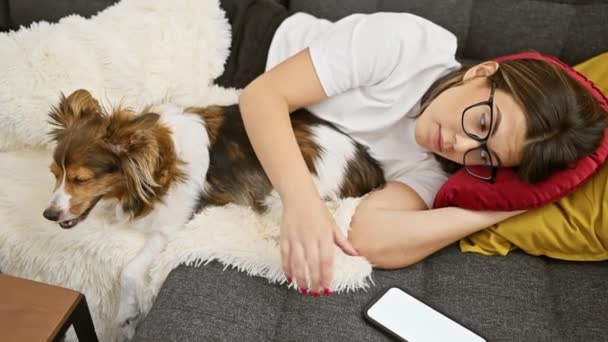 Gözlüklü Genç Kadın Evde Kanepede Uyuyan Köpeğin Yanında Uzanmış Mesajlaşırken — Stok video
