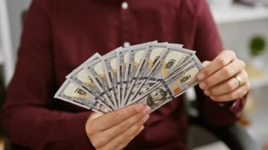 Ofisteki İspanyol bir adamın elinde 100 dolarlık banknotlar var..