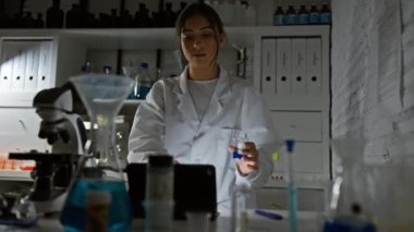 İspanyol kadın bilim adamı bir araştırma laboratuvarında mavi sıvıyı analiz ediyor.