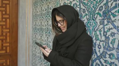 Türkçe karoları olan akıllı telefon kullanan tesettürlü kadın, İstanbul Topkapı Sarayı.
