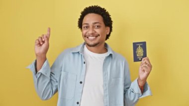 Kanada pasaportlu genç Afrikalı Amerikalı bir adam bir fikir veya soruyla gülümsüyor mutlu yüzüyle işaret ediyor, izole edilmiş sarı arka planda bir numara.