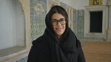 İstanbul 'da süslü bir Topkapı sarayında gözlüklü ve başörtülü gülümseyen bir kadın, hindi..