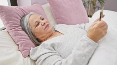 Yatak odasında pembe yastıklar ve beyaz çarşaflarla akıllı telefon kullanmasına şaşırdım.