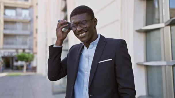 笑顔のスタイリッシュなアフリカ人男性 都市の街路でメガネを調整 — ストック動画