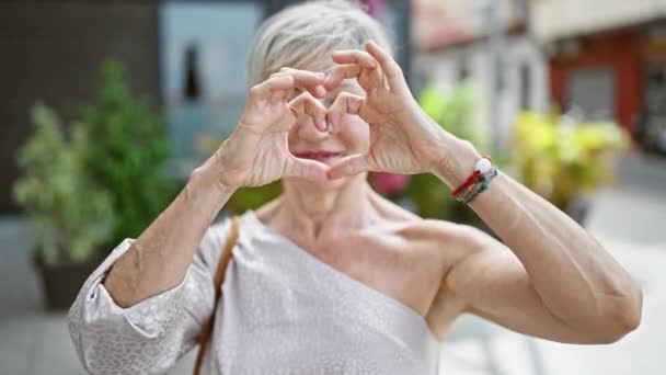 Mulher Madura Alegre Formando Coração Com Mãos Uma Rua Ensolarada — Vídeo de Stock