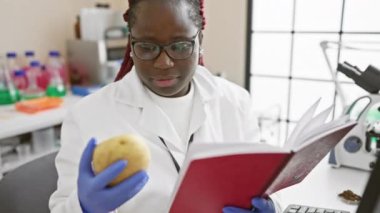 Afrikalı bilim adamı bir laboratuvarda notları okurken patatesi analiz ediyor..