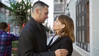 Sevgi dolu bir çift, şehir arka planında romantizm tasvir eden bir şehir caddesinde sarılıyor..