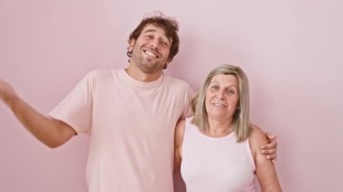 Mutlu anne ve oğul birlikte kazanmayı kutluyor, başarının başarısını ve heyecanını yayıyor. İzole edilmiş pembe arka planda kazanan yüz ifadesiyle gülümsüyor. saf aile zaferi!