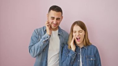 Kot gömlekli mutsuz, güzel bir çift, diş ağrısı çekiyorlar, acı ifadeleri sergiliyorlar, pembe izole edilmiş arka planda duruyorlar. Diş hastalığı, dişçi bakımı konsepti