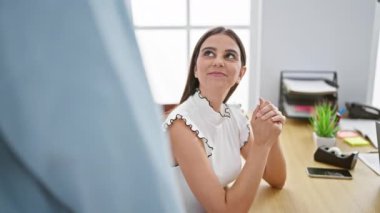 Parlak, modern ofis ortamında iş arkadaşıyla konuşurken gülümseyen kadın pozitiflik ve takım çalışması sergiliyor..