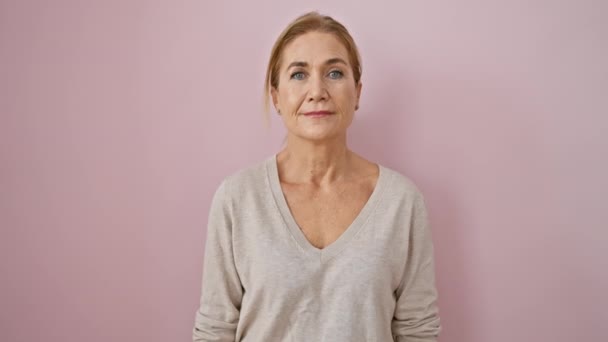 美しい中年のブロンドの女性は自信を持って歯の笑顔を欠いている 孤立したピンクの背景に肯定的なキャスティング — ストック動画