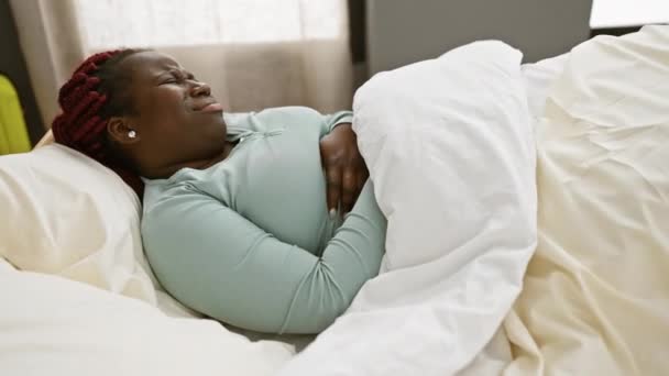 苦しんでいるアフリカの女性 クリニックのベッドでブレードで彼女の胃を締め 痛みを表現 — ストック動画