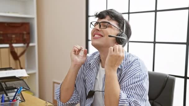 Cheerful Man Glasses Headset Gesturing Bright Office Shelves Window — Stock Video