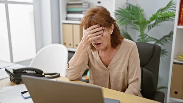 中年妇女在办公室里 用手指捂住脸 震惊地偷看 看上去很腼腆 但却对笔记本电脑感到惊讶 — 图库视频影像