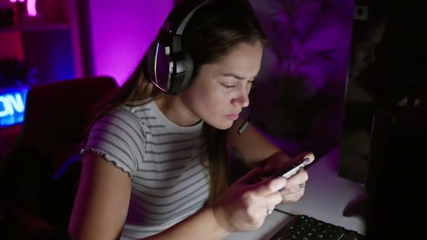 在灯光昏暗的游戏室里 专心致志的女人戴着智能手机 — 图库视频影像