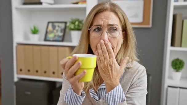 Mature Blonde Woman Yawning Yellow Mug Modern Office Setting — Stock Video