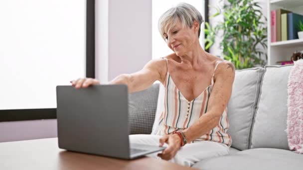Mulher Sênior Elegante Usando Laptop Sofá Casa Irradiando Confiança Conforto — Vídeo de Stock