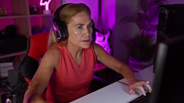 Kulaklıklı Olgun Bir Kadın Geceleri Neon Işıklı Bir Oyun Odasında — Stok video