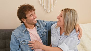 Oturma odasındaki kanepede birlikte oturan, samimi evlerinde neşeyle sarılıp gülümseyen, mutluluk ve güven saçan anne ve oğul..