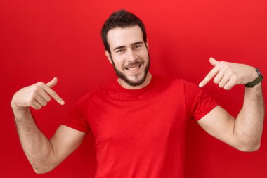 Gündelik kırmızı tişört giyen genç İspanyol adam kendine güvenen, yüzünde gülümseme olan, kendini gururlu ve mutlu bir şekilde gösteren.. 
