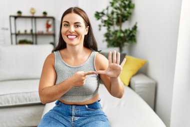 Genç ve güzel İspanyol kadın evdeki kanepede oturan sağırlarla iletişim kuruyor.