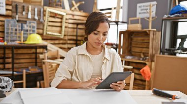 Güzel, genç bir İspanyol kadın marangoz. Bağımsız atölyesinde dokunmatik ped kullanarak marangozluk işini ustalıkla yönetiyor..