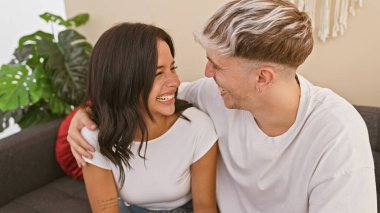 Gülümseyen bir adam ve kadın evlerinin oturma odasında sevgi ve dostluk iletiyorlar..