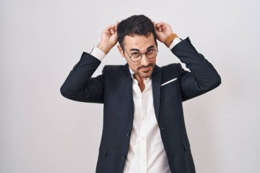 Beyaz arka planda dikilen yakışıklı İspanyol bir adam komik ve deli pozu veriyor parmakları kafasında tavşan kulağı, neşeli bir gülümseme 