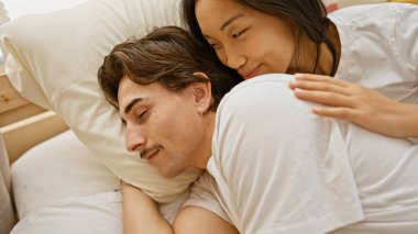 Sıcak bir yatak odasında birbirine sarılan, sıcaklığı ve sevgiyi yansıtan sevgi dolu ırklar arası bir çift..