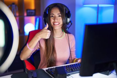 Genç İspanyol kadın video oyunları oynuyor. Elleriyle mutlu bir jest yapıyor. Kameraya bakıp başarıyı gösteren ifade. 