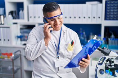 Genç Latin bilim adamı laboratuvarda akıllı telefon okuyarak konuşuyor.
