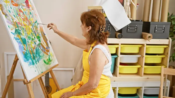 Зрелая Женщина Рисует Холсте Яркой Студии Демонстрируя Творчество Отдых Художественной — стоковое фото