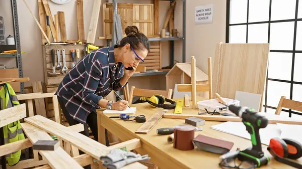Hispanic Woman Talking Phone While Working Carpentry Workshop Surrounded Woodworking — Stock Photo, Image