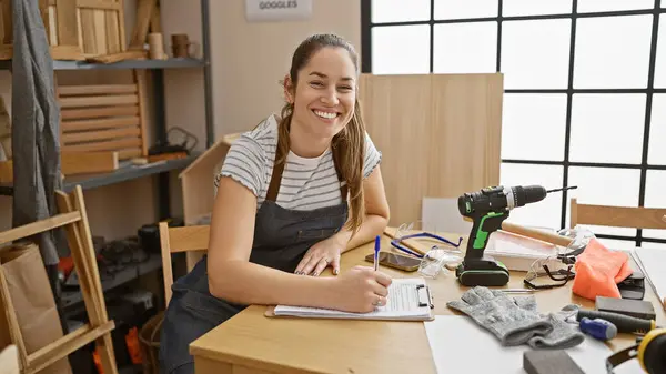 Smiling Woman Wearing Apron Sits Desk Sunny Carpentry Workshop Surrounded — Stock Photo, Image