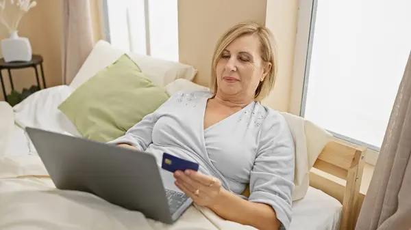 Reife Blonde Frau Mit Kreditkarte Und Laptop Schlafzimmer — Stockfoto
